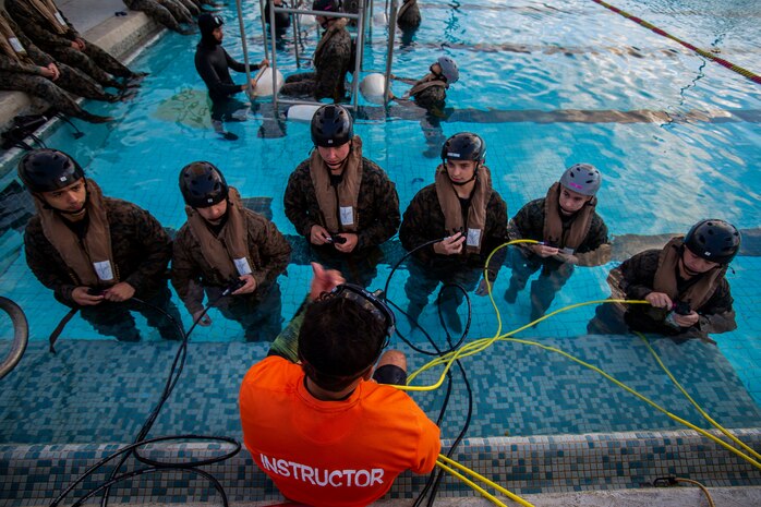 An underwater egress training instructor with Marine Corps Base Hawaii teaches U.S. Marines with Headquarters Battalion, MCBH, how to use the Emergency Breathing System during Helicopter Underwater Egress Training, MCBH, Feb. 27, 2020. The training provides Marines with confidence to safely and efficiently exit a submerged aircraft in the event of a water landing. (U.S. Marine Corps photo by Cpl. Matthew Kirk)