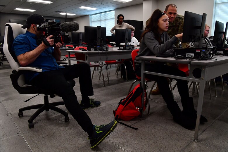 Chris Wright, Optix Creative principal and director of photography, films U.S. Air Force 1st Lt. Thomas Van Dorple, 223rd Cyberspace Operations Squadron flight commander, speaking with a student from Jacksonville High School.