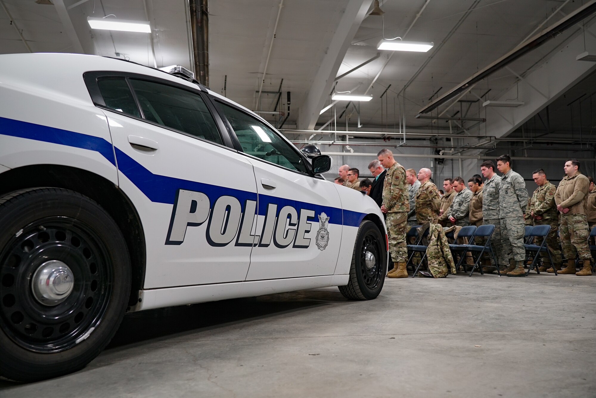 Members of the 319th Security Forces Squadron bow their heads during a memorial service Dec. 20, 2019, on Grand Forks Air Force Base, North Dakota. The service honored the life of 319th Security Forces military working dog, “Dex.” Dex worked as a narcotic detector dog for five years on Grand Forks AFB, alongside local law enforcement, U.S. Air Force Office of Special Investigations, and U.S. Customs and Border Protection. (U.S. Air Force photo by Senior Airman Elora J. Martinez)