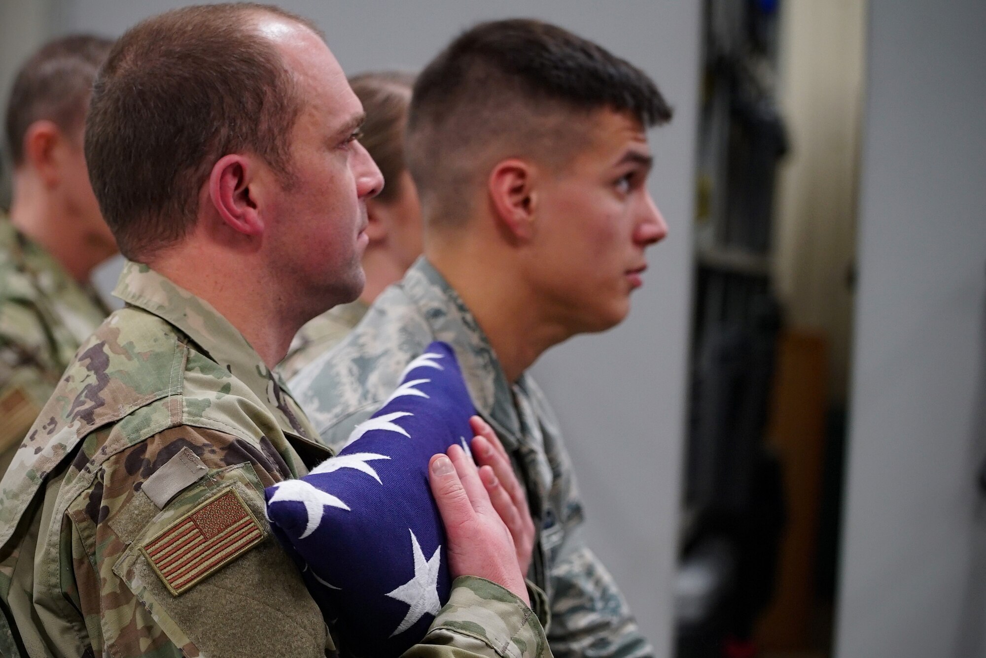 Staff Sgt. Sean King, 319th Security Forces Squadron military working dog handler, left, squeezes a U.S. flag to his chest during a memorial service for his partner, “Dex,” Dec. 20, 2019, on Grand Forks Air Force Base, North Dakota. King was Dex’s most recent handler, previously working alongside nine other defenders throughout his career as a narcotic detector dog. (U.S. Air Force photo by Senior Airman Elora J. Martinez)