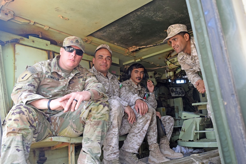 4 Jordanian and US Soldiers sit together in Army vehicle