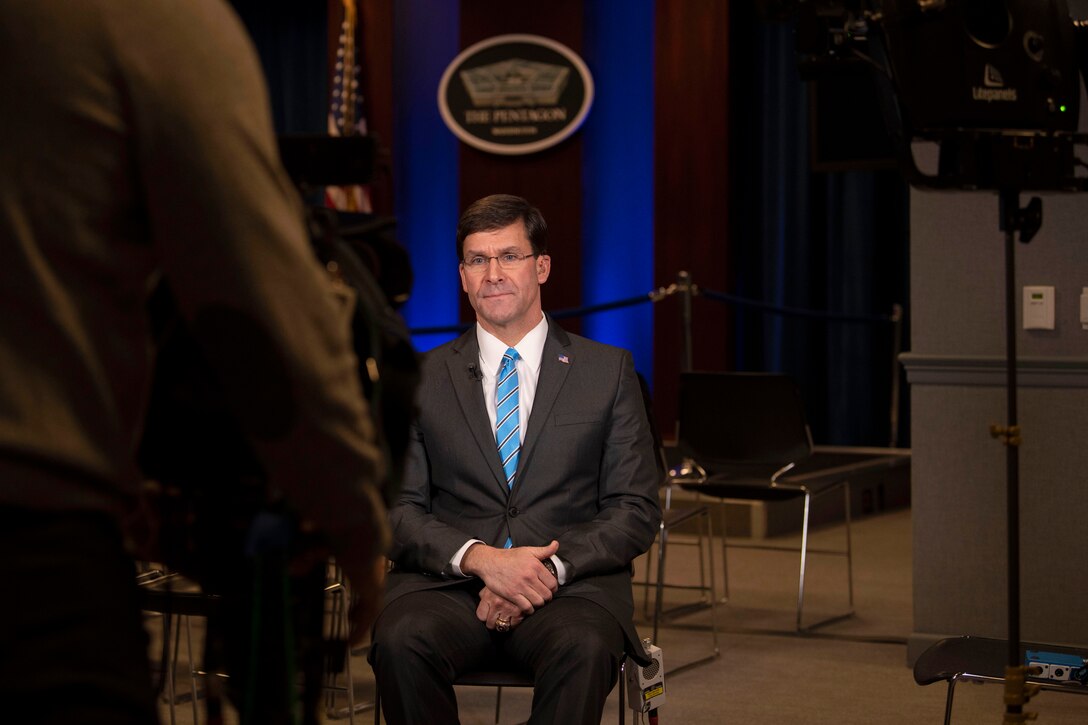 Defense Secretary Dr. Mark T. Esper sits in a room with broadcast equipment around him.