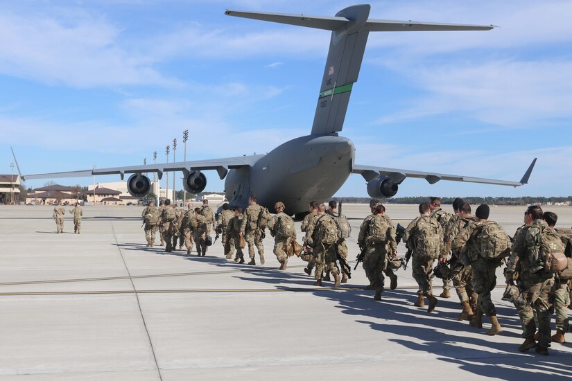 Soldiers line up to get on a military aircraft.