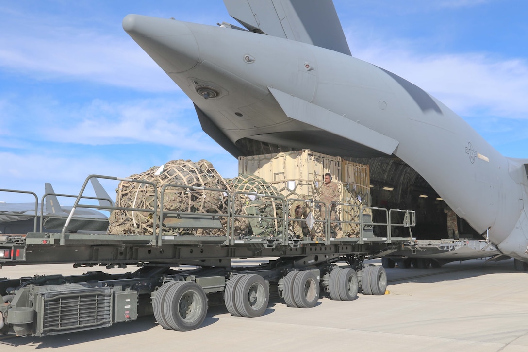 Cargo is loaded into the back end of a military aircraft.