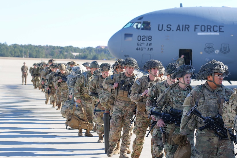 Soldiers walk across a flight line.