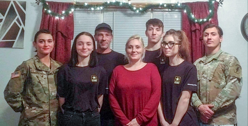 five siblings, two in uniform and both parents pose for a family photo.