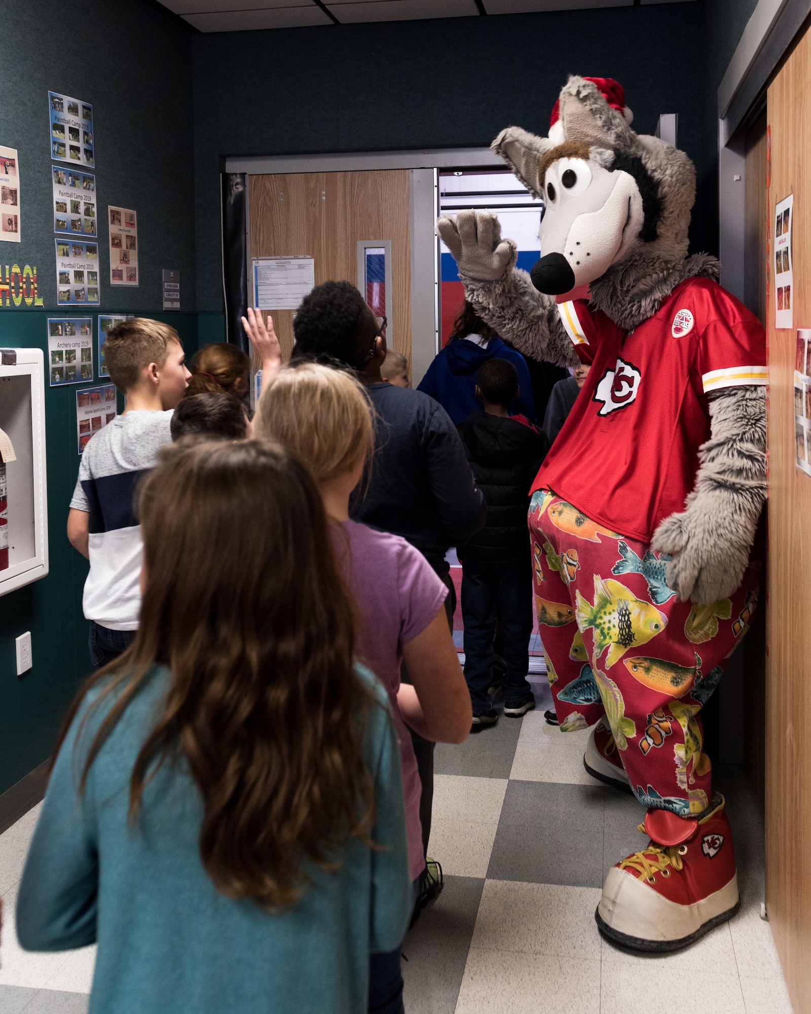 Dan Meers, the Kansas City Chiefs NFL team mascot KC Wolf, welcomes children at the Youth Center, Whiteman Air Force Base, Missouri, Dec. 18, 2019. Meers talked to the children about the importance of your attitude, behavior and character and answered questions about what life is like as a mascot as part of an outreach to positively influence their overall well-being and promote resiliency. (U.S. Air Force photo by Airman 1st Class Christina Carter)