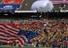 Photo of a U.S. Air Force skydiving team member parachuting with a U.S. flag onto a football field