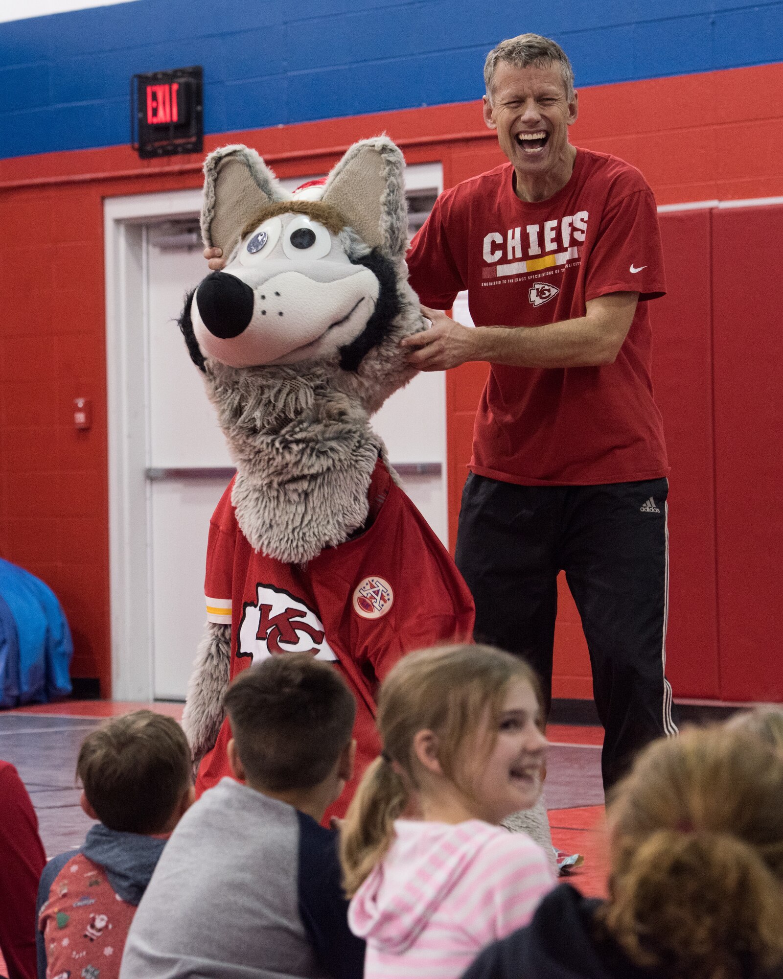 Dan Meers, the Kansas City Chiefs NFL team mascot KC Wolf, demonstrated how he gets dressed for work by allowing a volunteer to wear his suit at the Youth Center, Whiteman Air Force Base, Missouri, Dec. 18, 2019. Meers talked to the children about the importance of your attitude, behavior and character and answered questions about what life is like as a mascot as part of an outreach to positively influence their overall well-being and promote resiliency. (U.S. Air Force photo by Airman 1st Class Christina Carter)