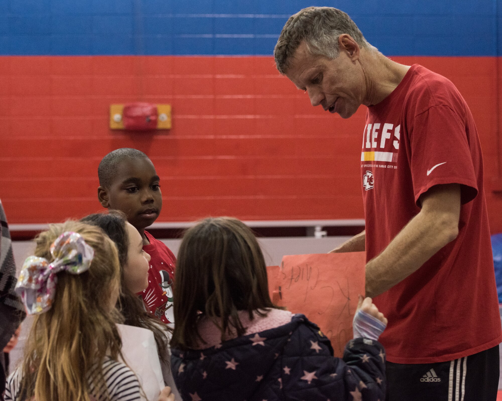 Dan Meers, the Kansas City Chiefs NFL team mascot KC Wolf, receives pictures made by the children at the Youth Center, Whiteman Air Force Base, Missouri, Dec. 18, 2019. Meers talked to the children about the importance of your attitude, behavior and character and answered questions about what life is like as a mascot as part of an outreach to positively influence their overall well-being and promote resiliency. (U.S. Air Force photo by Airman 1st Class Christina Carter)