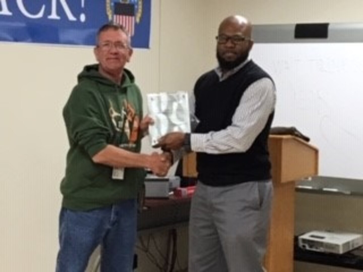 Operations Chief Willie Mitchell presents Disposal Service Representative Dave Smith with a plaque from Veterans Administration for helping the agency find usable items to aid homeless vets.