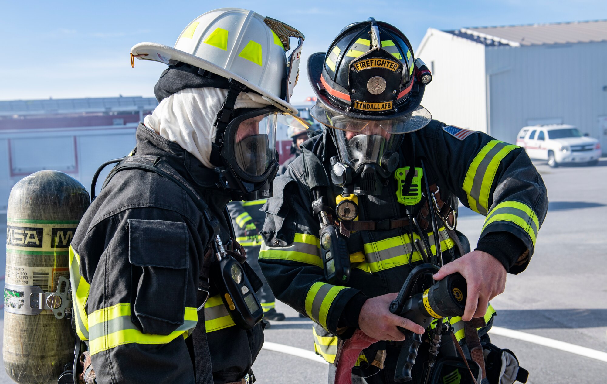 U.S. Air Force Senior Airman Christian Gosnell, 325th Civil Engineer Squadron driver operator (right), instructs U.S. Air Force Col. Brian Laidlaw, 325th Fighter Wing commander (left), how to operate a fire hose before a simulated burning building exercise at Tyndall Air Force Base, Fla., Dec. 20, 2019. Gosnell has been an Air Force fire fighter at Tyndall for six years. (U.S. Air Force photo by Senior Airman Stefan Alvarez)