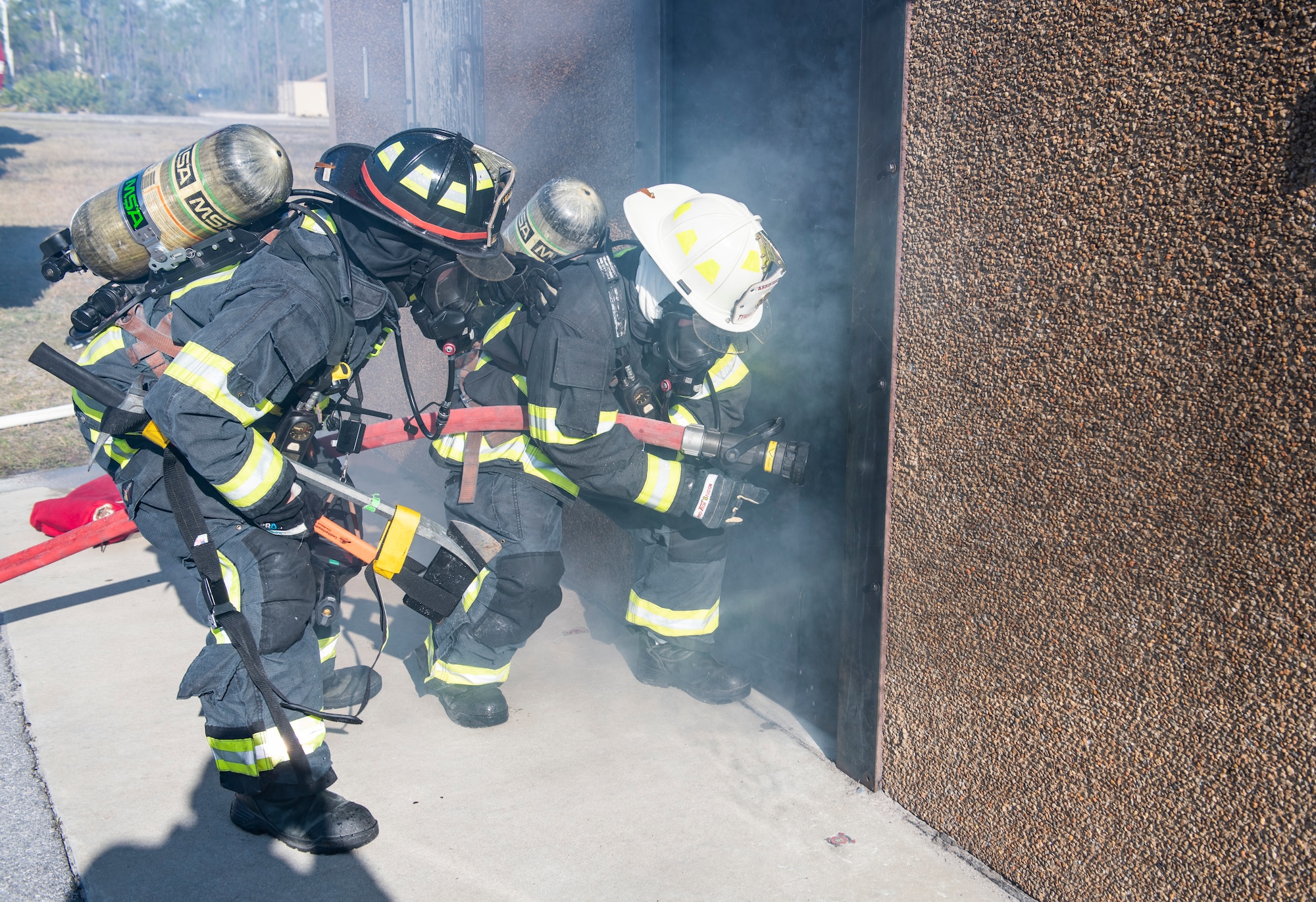 U.S. Air Force Senior Airman Christian Gosnell, 325th Civil Engineer Squadron driver operator (left), assists U.S. Air Force Col. Brian Laidlaw, 325th Fighter Wing commander (right), with operating a fire hose during a simulated burning building exercise at Tyndall Air Force Base, Fla., Dec. 20, 2019. Gosnell was selected to have the wing commander come out and have a hands on experience with his job at the fire department. (U.S. Air Force photo by Senior Airman Stefan Alvarez)