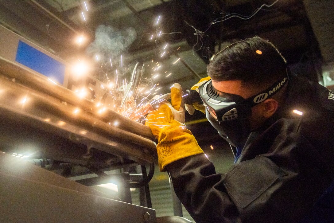 Sparks fly as an airman uses a welder.