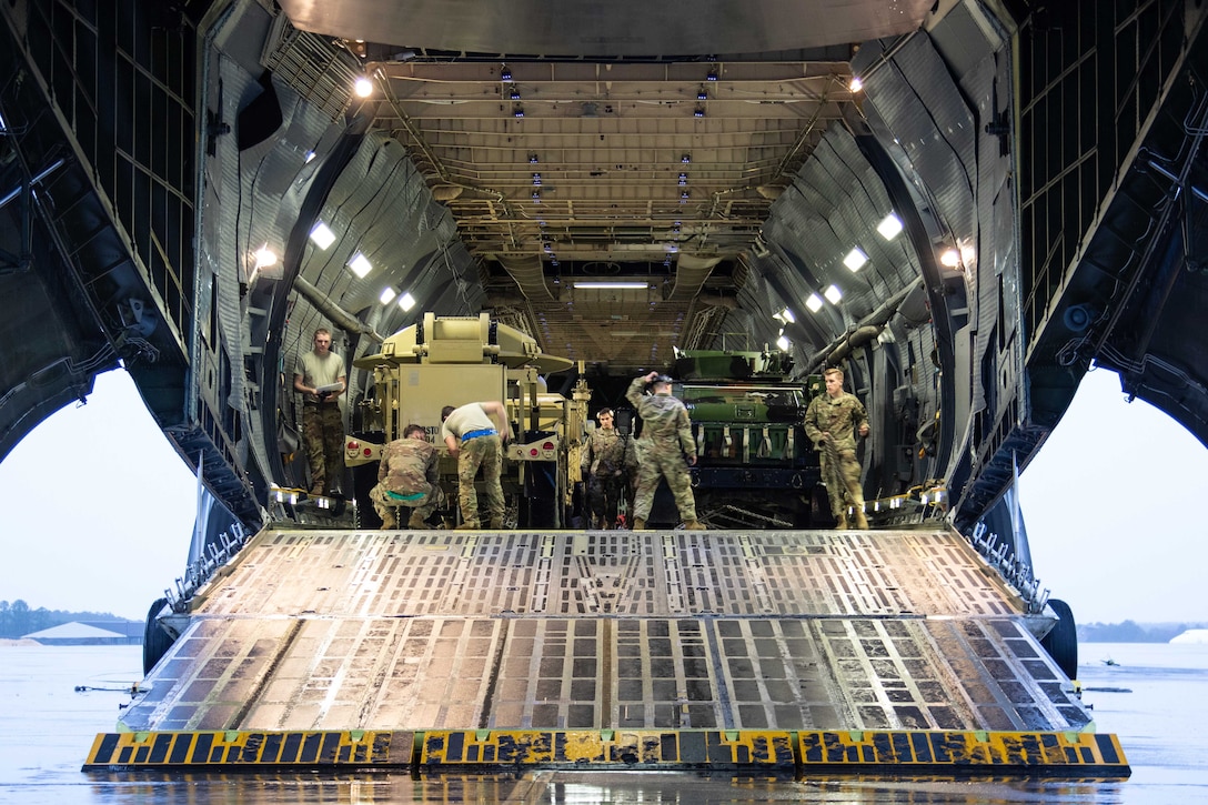 Soldiers load equipment into a large military aircraft.