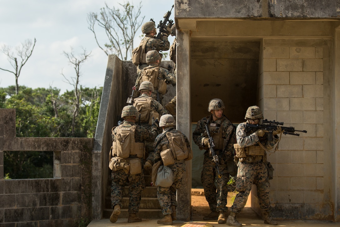 Marines move up a set of stairs while clearing buildings during a simulated raid of a hostile town at the Central Training Area, Okinawa, Japan, Dec. 9.
