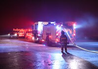 Firefighters lay out a hose Dec. 28, 2019, at Minot Air Force Base, North Dakota. The fire trucks pressurize water to extinguish the flames. (U.S. Air Force Photos By Airman 1st Class Caleb S. Kimmell)