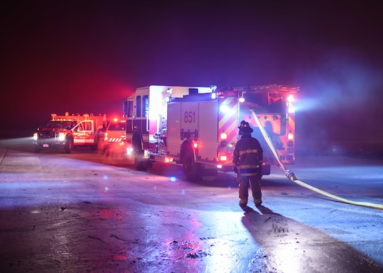 Firefighters lay out a hose Dec. 28, 2019, at Minot Air Force Base, North Dakota. The fire trucks pressurize water to extinguish the flames. (U.S. Air Force Photos By Airman 1st Class Caleb S. Kimmell)