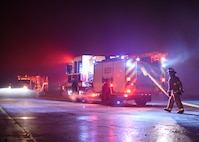 Firefighters circle a burning hangar Dec. 28, 2019, at Minot Air Force Base, North Dakota. The 5th Civil Engineer Squadron assisted the firefighters by putting up large lights to illuminate the scene. (U.S. Air Force Photos By Airman 1st Class Caleb S. Kimmell)