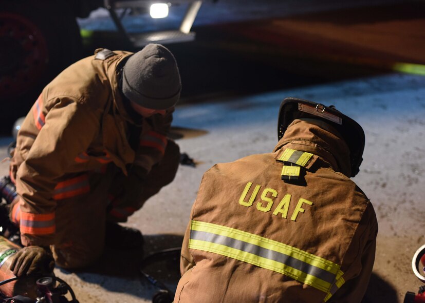 Firefighters lay out a hose Dec. 28, 2019, at Minot Air Force Base, North Dakota. The fire trucks pressurize water to extinguish the flames. (U.S. Air Force Photos By Airman 1st Class Caleb S. Kimmell)