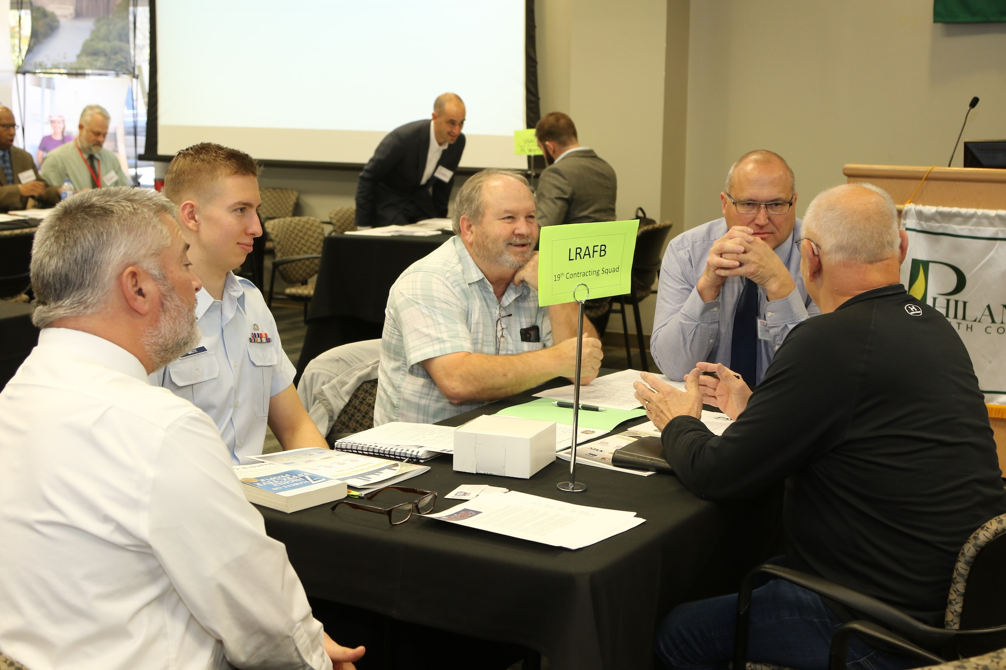 Airman and men sit around a table and discuss