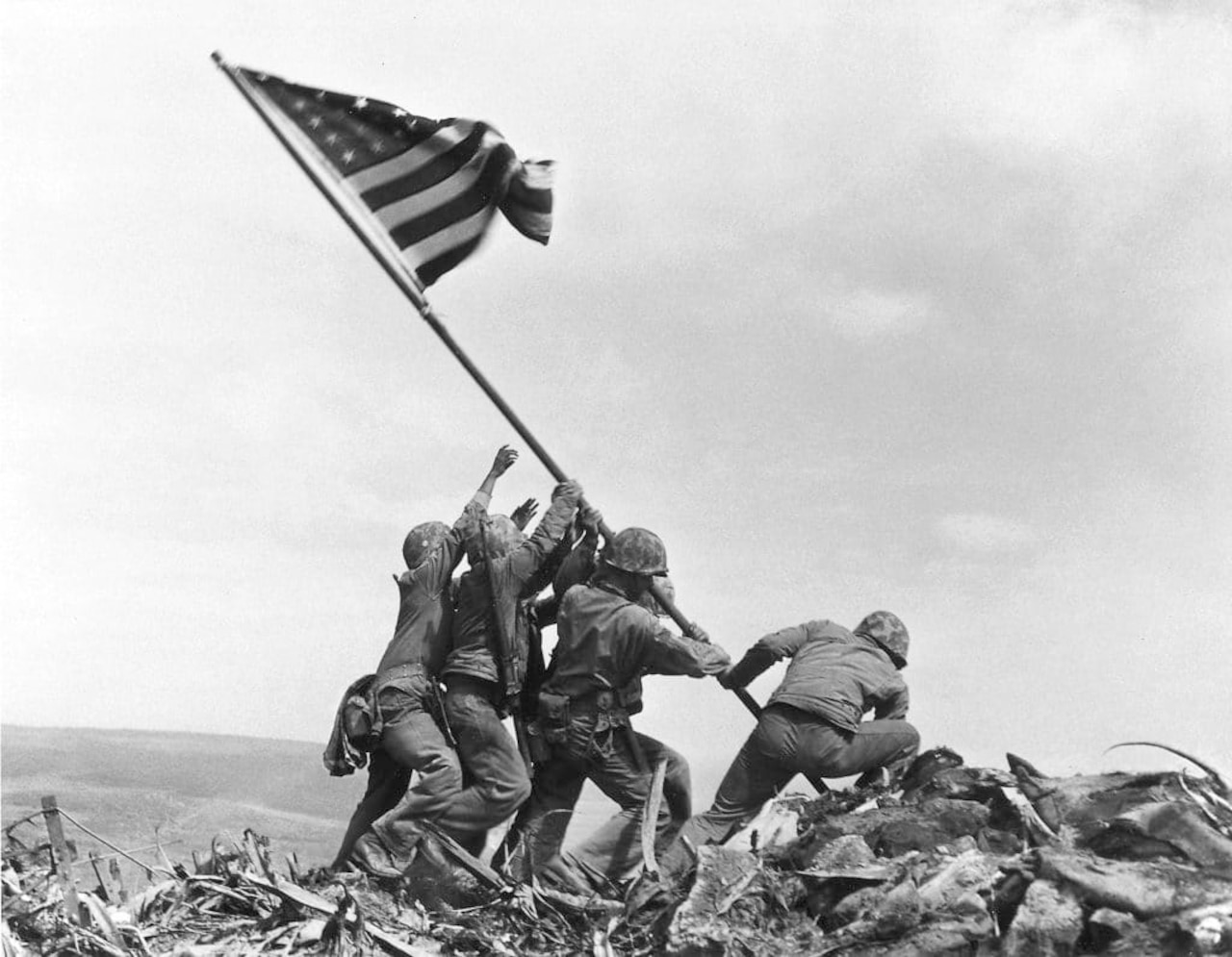 U.S. service members in combat gear raise a flag.