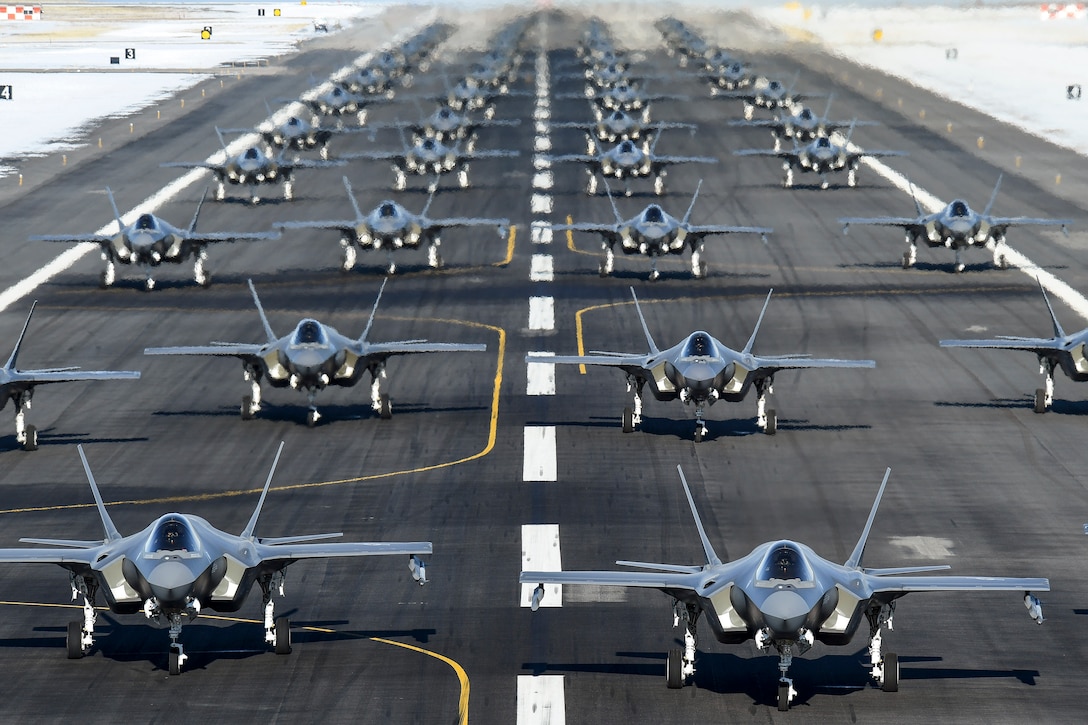Four long lines of F-35 aircraft are in formation on a flightline.