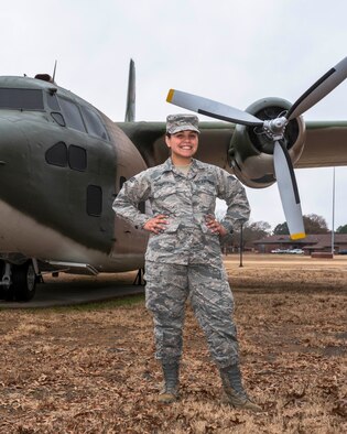 A woman stands in front of a plane.