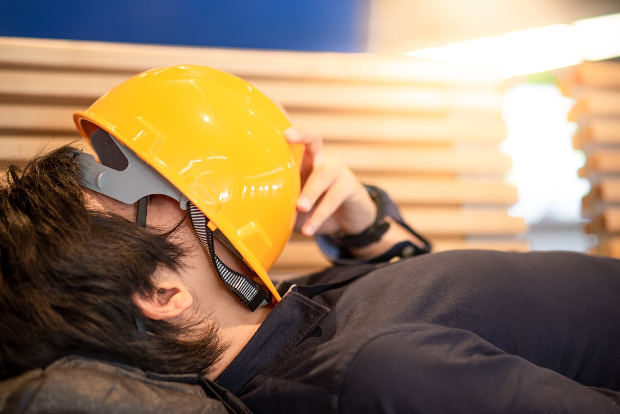 Photo shows laborer sleeping with hardhat laying across face.
