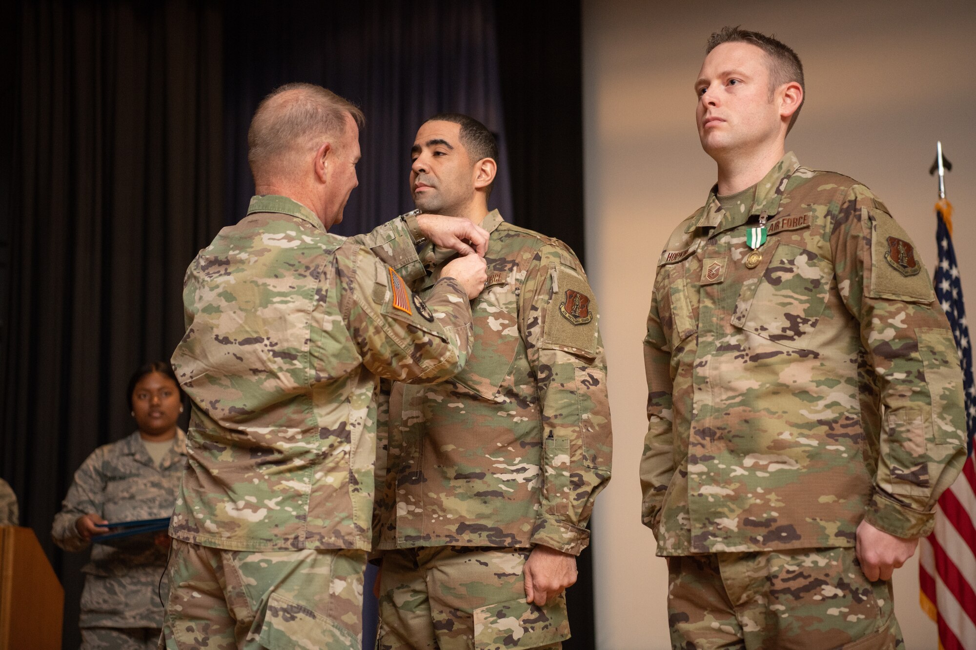 a general pins on a medal to two Airmen
