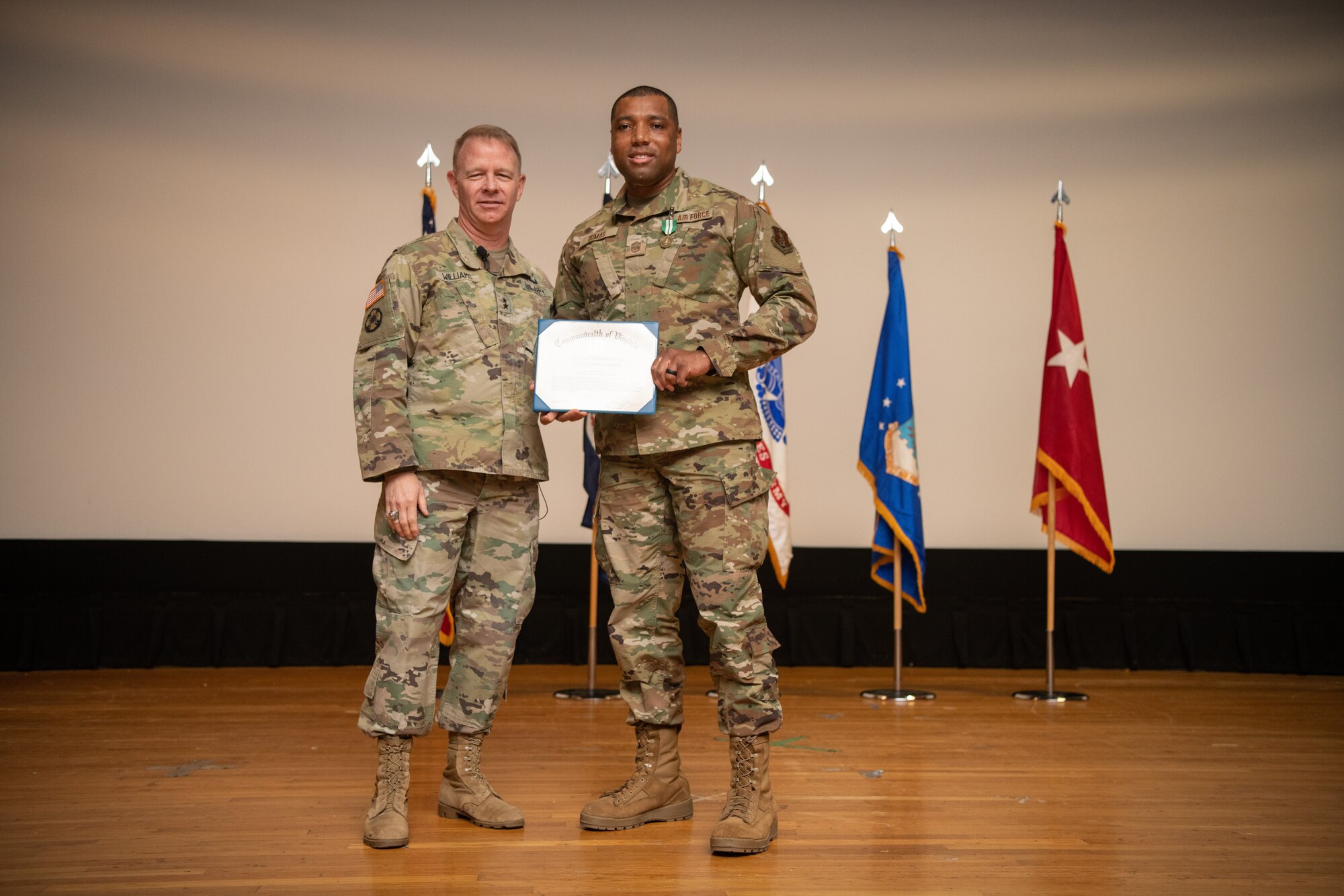 two Airmen pose with a certificate