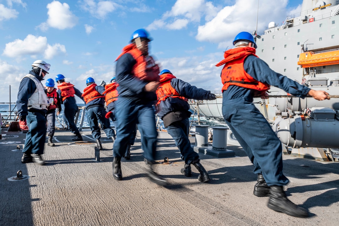A group of sailors pull on a rope.