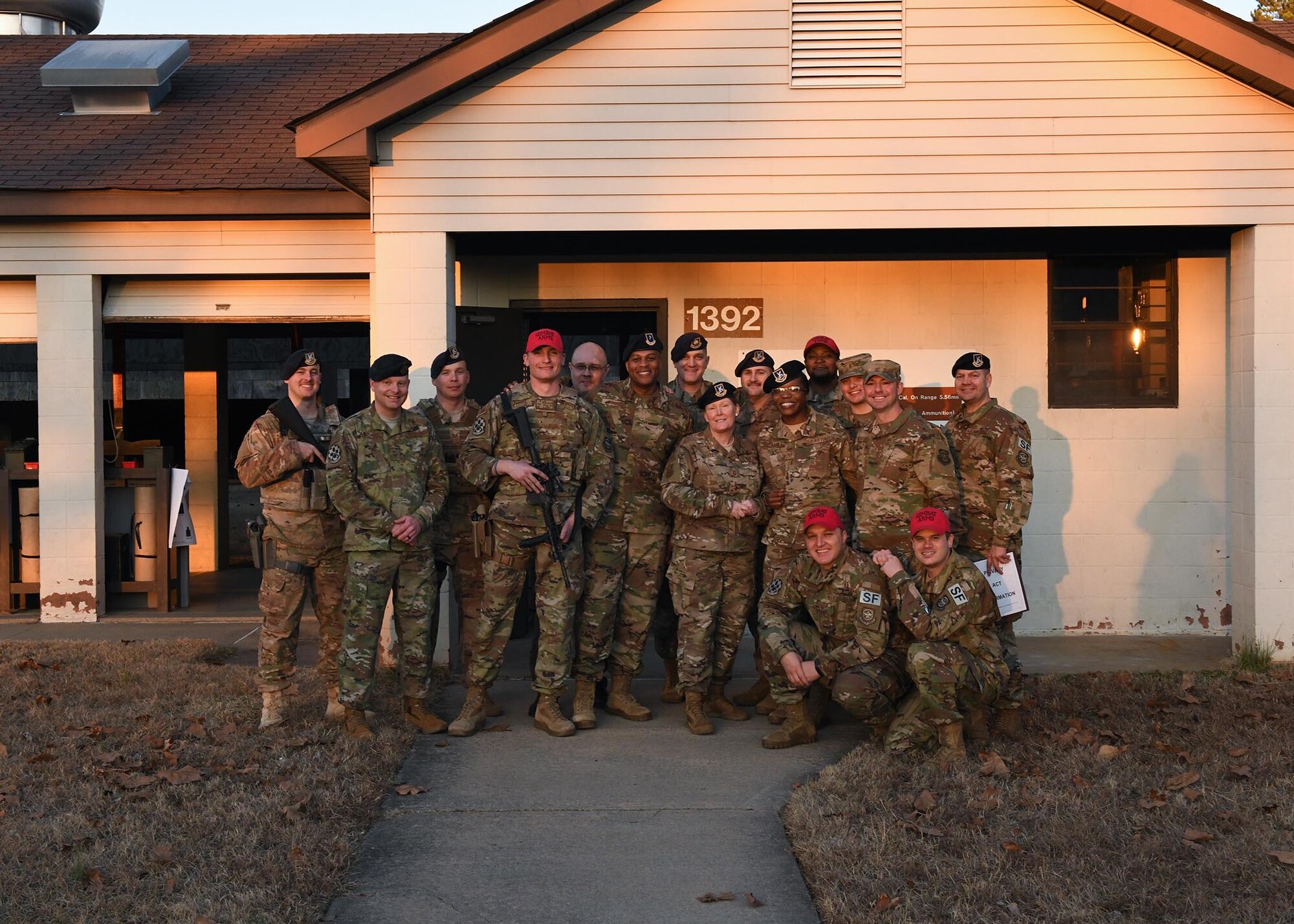 A group of Airmen pose for a picture in front of a building