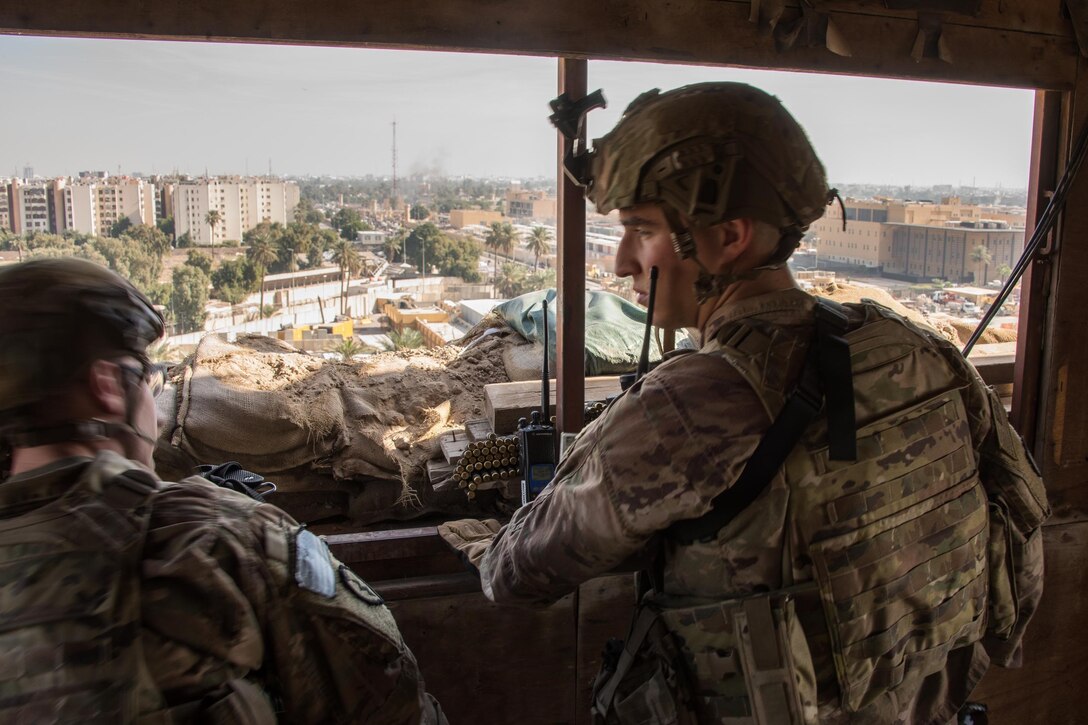 Two soldiers stand in a window of a guard tower.