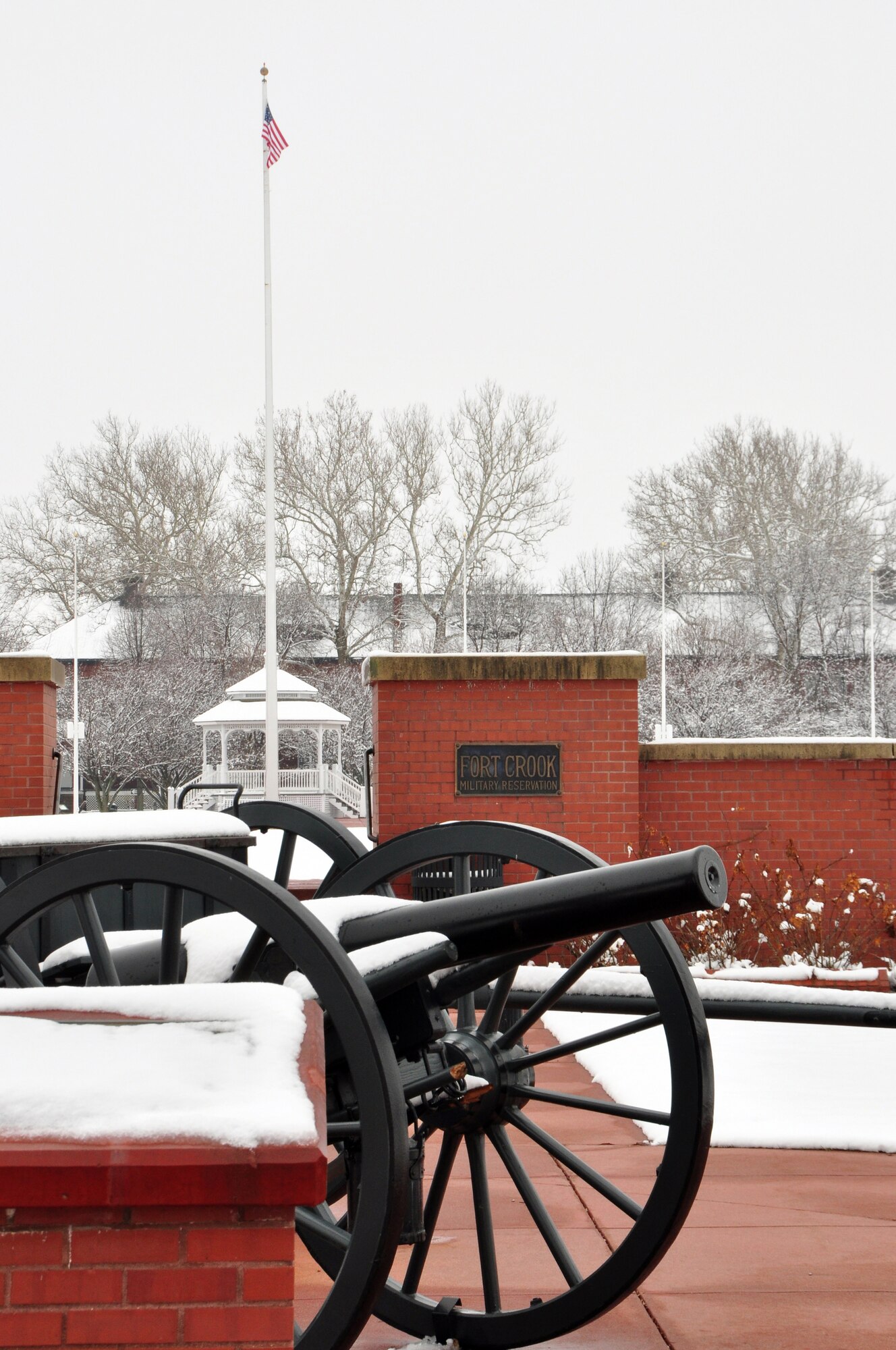 Offutt parade grounds, covered in snow, with cannon in foreground and gazebo in distant background