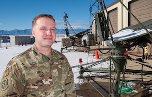 An Air Force Reserve enlisted member stands near satellite communications equipment