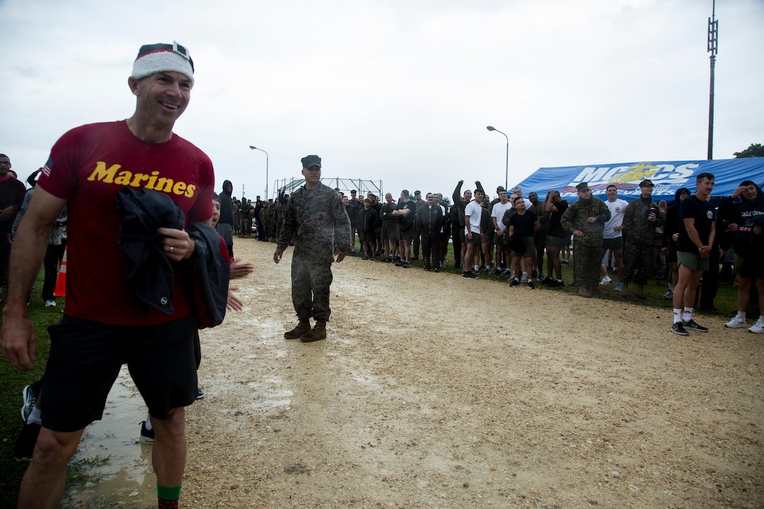 U.S. Marines with Marine Corps Air Station (MCAS) Futenma watch the relay runners during the Jingle Bell Challenge on MCAS Futenma, Okinawa, Japan, Dec. 6, 2019. The Jingle Bell challenge is a time for Marines who are far away from home to build unit morale during the holiday season. (U.S. Marine Corps photo by Cpl. Sarah  Stegall)