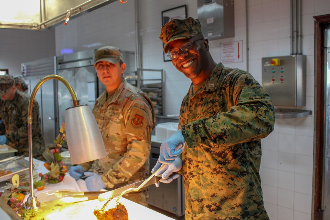 A U.S. Air Force airman with 496th Tactical Fighter Squadron, and a U.S. Marine with Special Purpose Marine Air-Ground Task Force-Crisis Response-Africa 20.1, Marine Forces Europe and Africa, serves Christmas food to fellow Marines and Sailors at Morón Air Base, Spain, Dec. 25, 2019. SPMAGTF-CR-AF is deployed to conduct crisis-response and theater-security operations in Africa and promote regional stability by conducting military-to-military training exercises throughout Europe and Africa. (U.S. Marine Corps photo by 2nd Lt. Andrew Soto)