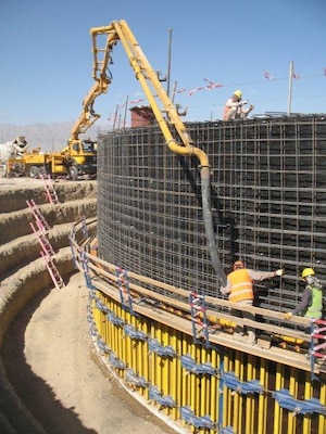 Workers use a boom concrete pump truck to place concrete around the metal shell of a Cut & Cover tank at Bagram Airfield, Afghanistan.  Each layer of concrete is allowed to set before additional concrete is placed, until the entire tank is protected by concrete.  (Photo by Clay Bolton)