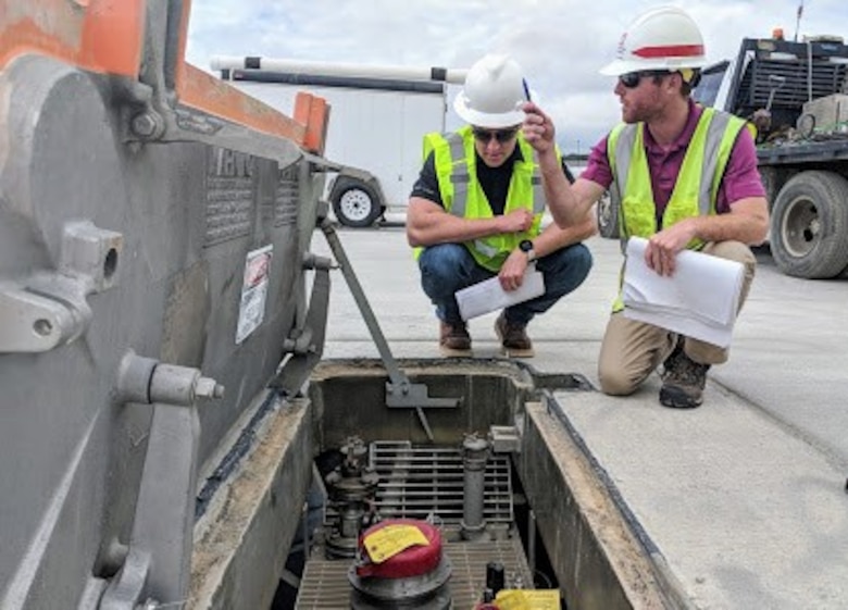 Matt Peterson (left), POL-MCX mechanical engineer, inspects a hydrant pit prior to tuning while Matthew Hoyle, Civil Engineer/Office Engineer, Savannah District, locates adjacent hydrant fuel pits along the Green Ramp at Pope Army Airfield, North Carolina.  (Photo by Greg Etter)