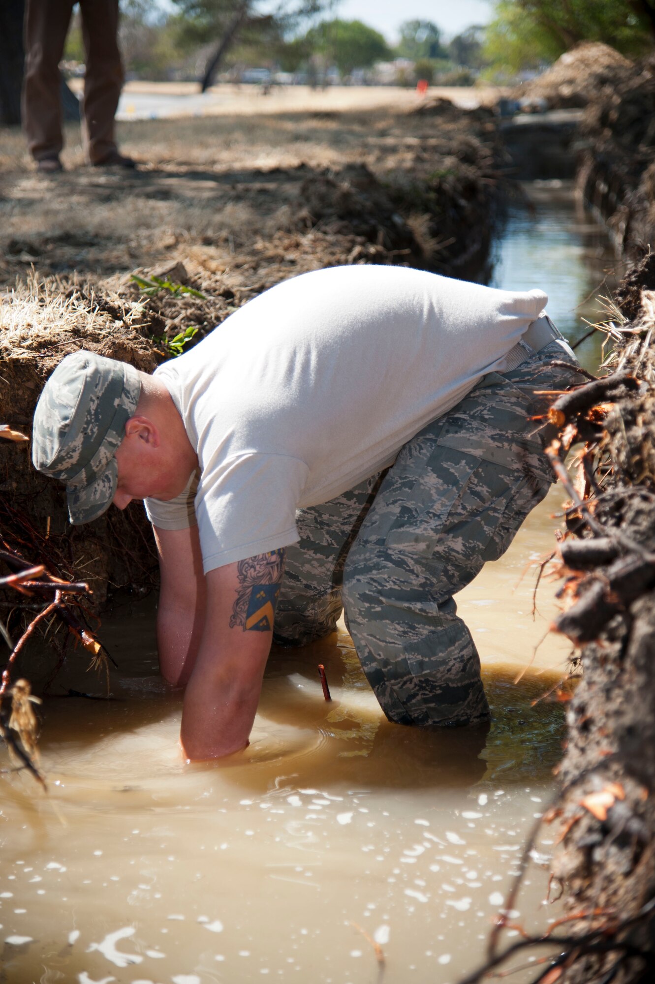 Senior Airman Steven Lynch, 60th Civil Engineer Squadron water and fuels maintenance craftsman, feels for a broken pipe after a water main break on base Aug. 27 to help the CE team decide their next course of action. (U.S. Air Force photo/Airman 1st Class Nicole Leidholm)