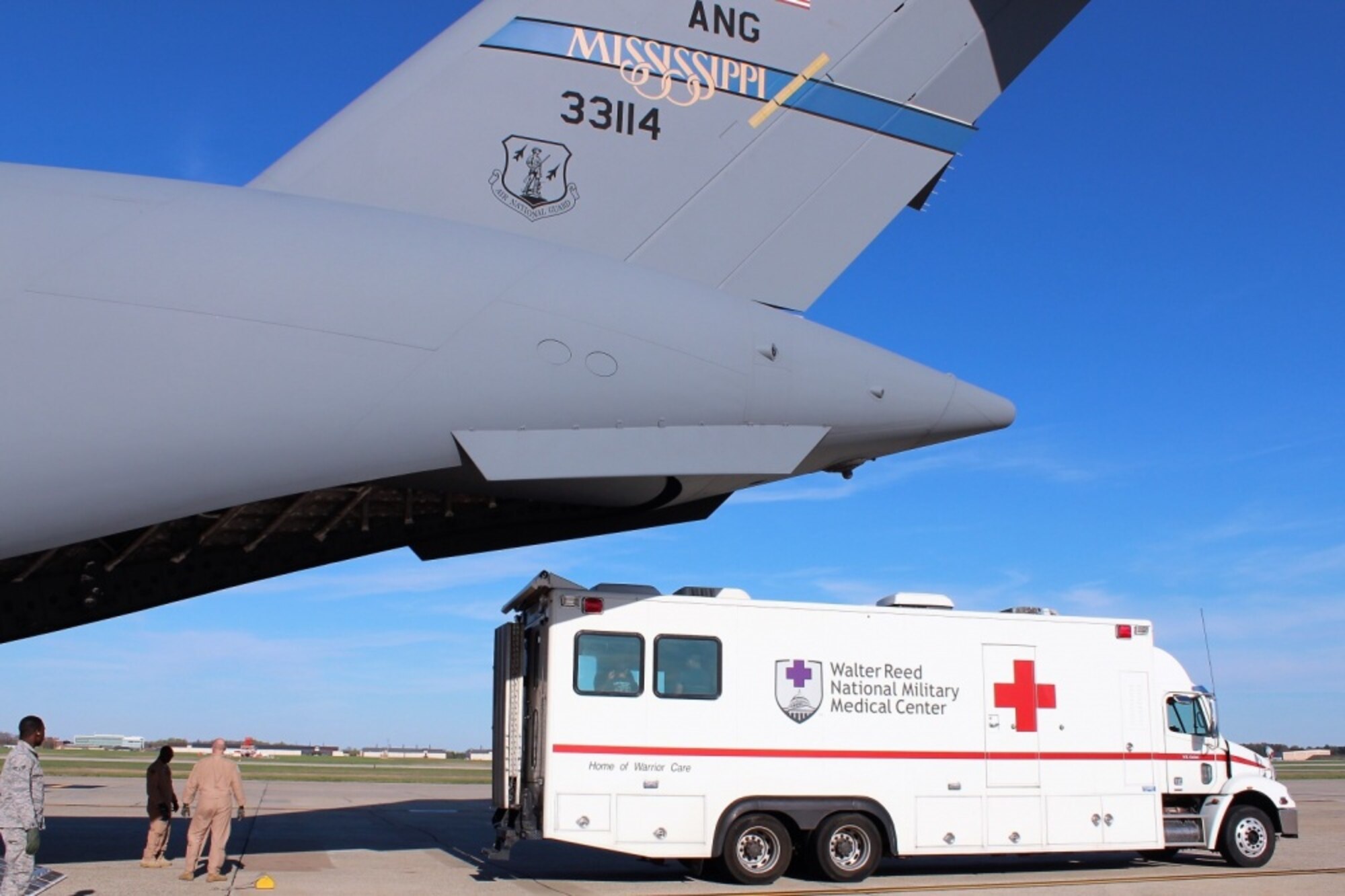 An ambulance bus backs up to the Mississippi Air National Guard C-17 Globemaster III as airmen prepare to unload patients at Joint Base Andrews, Maryland
