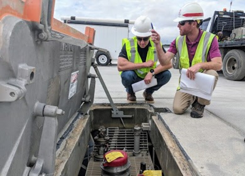 Matt Peterson (left), POL-MCX mechanical engineer, inspects a hydrant pit prior to tuning while Matthew Hoyle, Civil Engineer/Office Engineer, Savannah District, locates adjacent hydrant fuel pits along the Green Ramp at Pope Army Airfield, North Carolina.  (Photo by Greg Etter)