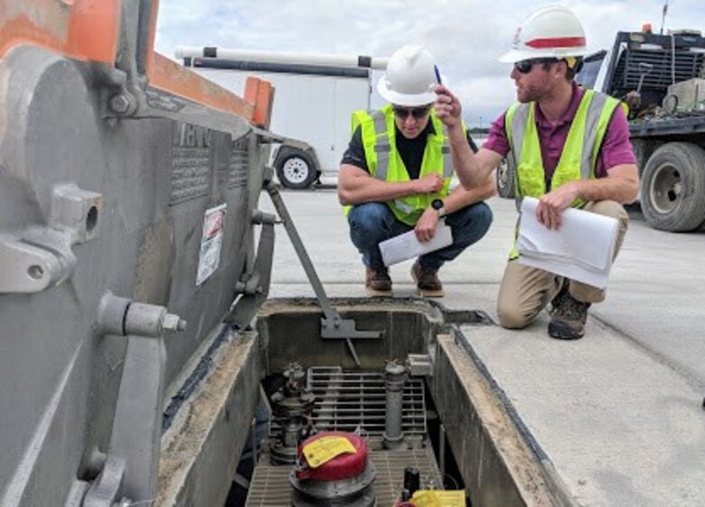 Matt Peterson (left), POL-MCX mechanical engineer, inspects a hydrant pit prior to tuning while Matthew Hoyle, Civil Engineer/Office Engineer, Savannah District, locates adjacent hydrant fuel pits along the Green Ramp at Pope Army Airfield, North Carolina.  (Photo by Greg Etter)