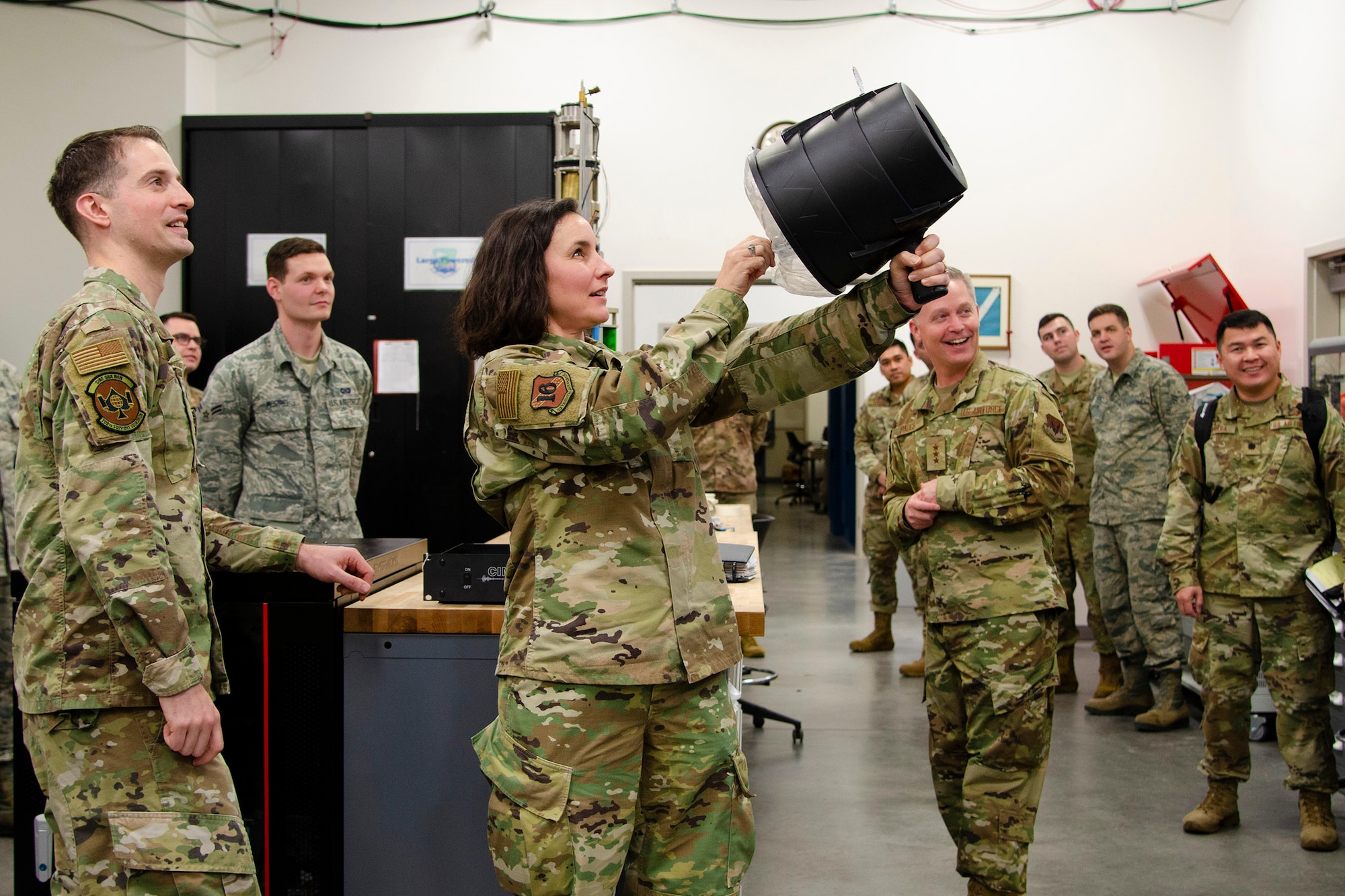 Chief Master Sgt. Summer Leifer (center), 16th Air Force Command Chief, sends a burst of air using an air cannon at a hybrid seismic-infrasound sensor that's being tested by Central Repair Facility Airmen at the Air Force Technical Applications Center, Patrick AFB, Fla.  Leifer and 16th Air Force Commander Lt. Gen. Timothy Haugh (right/center, smiling), visited the nuclear treaty monitoring center Dec. 16, 2019 to get an up-close look at how AFTAC plays a critical role in the Numbered Air Force’s overarching intelligence, surveillance, reconnaissance, cyber and electronic warfare mission.  (U.S. Air Force photo by Susan A. Romano)