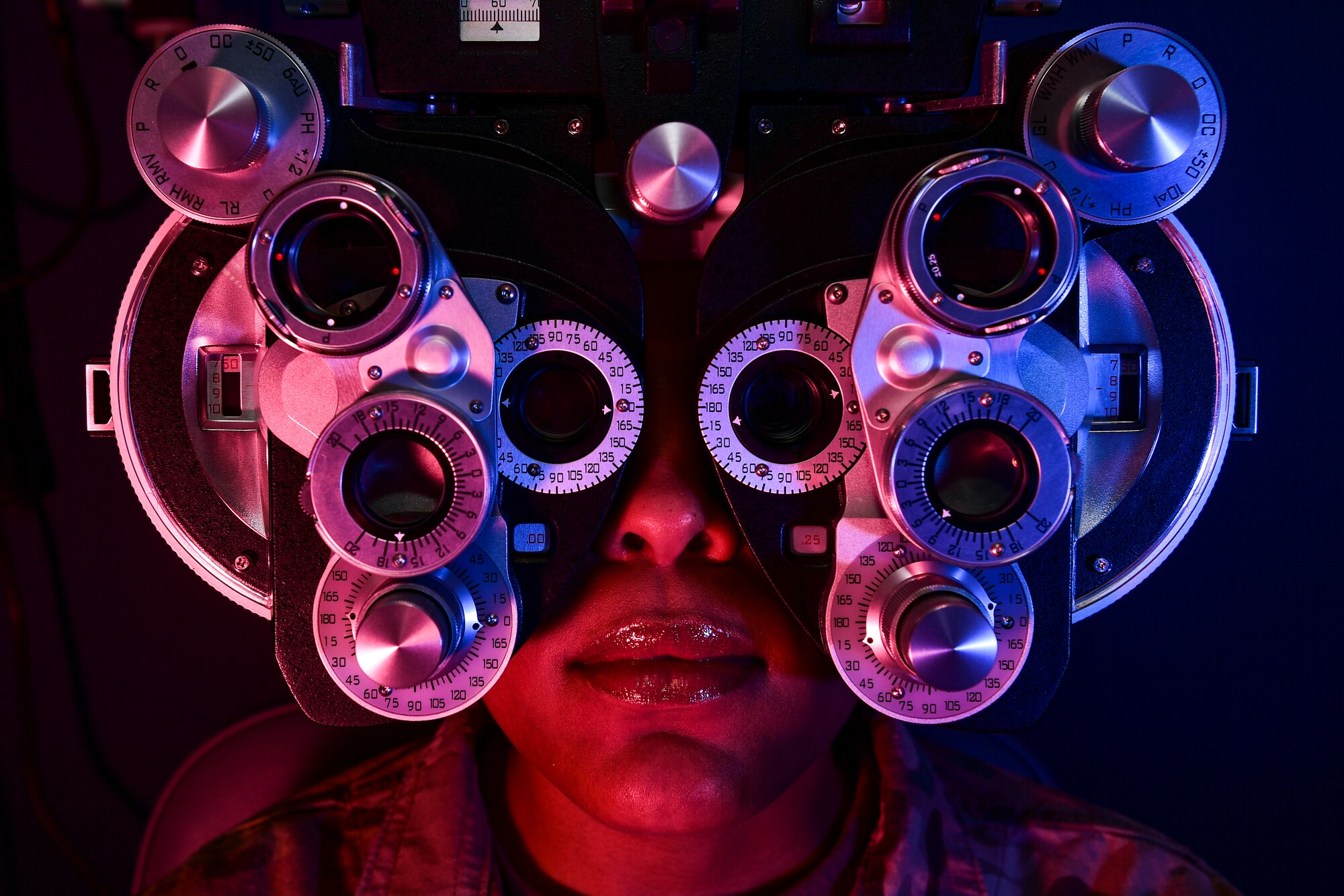 A patient looks through a phoropter during an eye examination training session