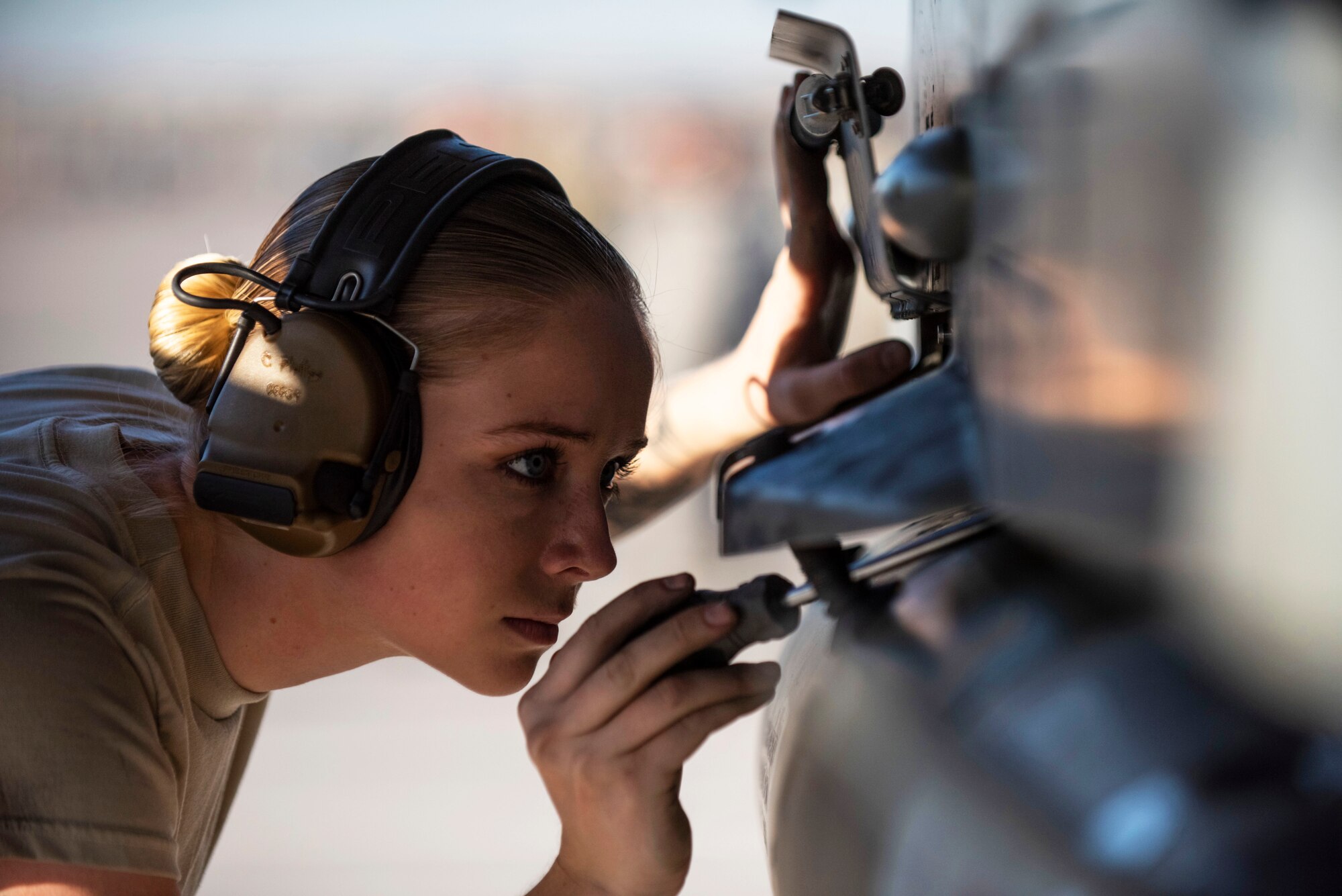 Senior Airman secures munitions in place on an F-16 Fighting Falcon