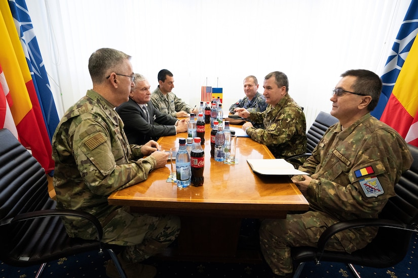 A group of military officers sit around a table.