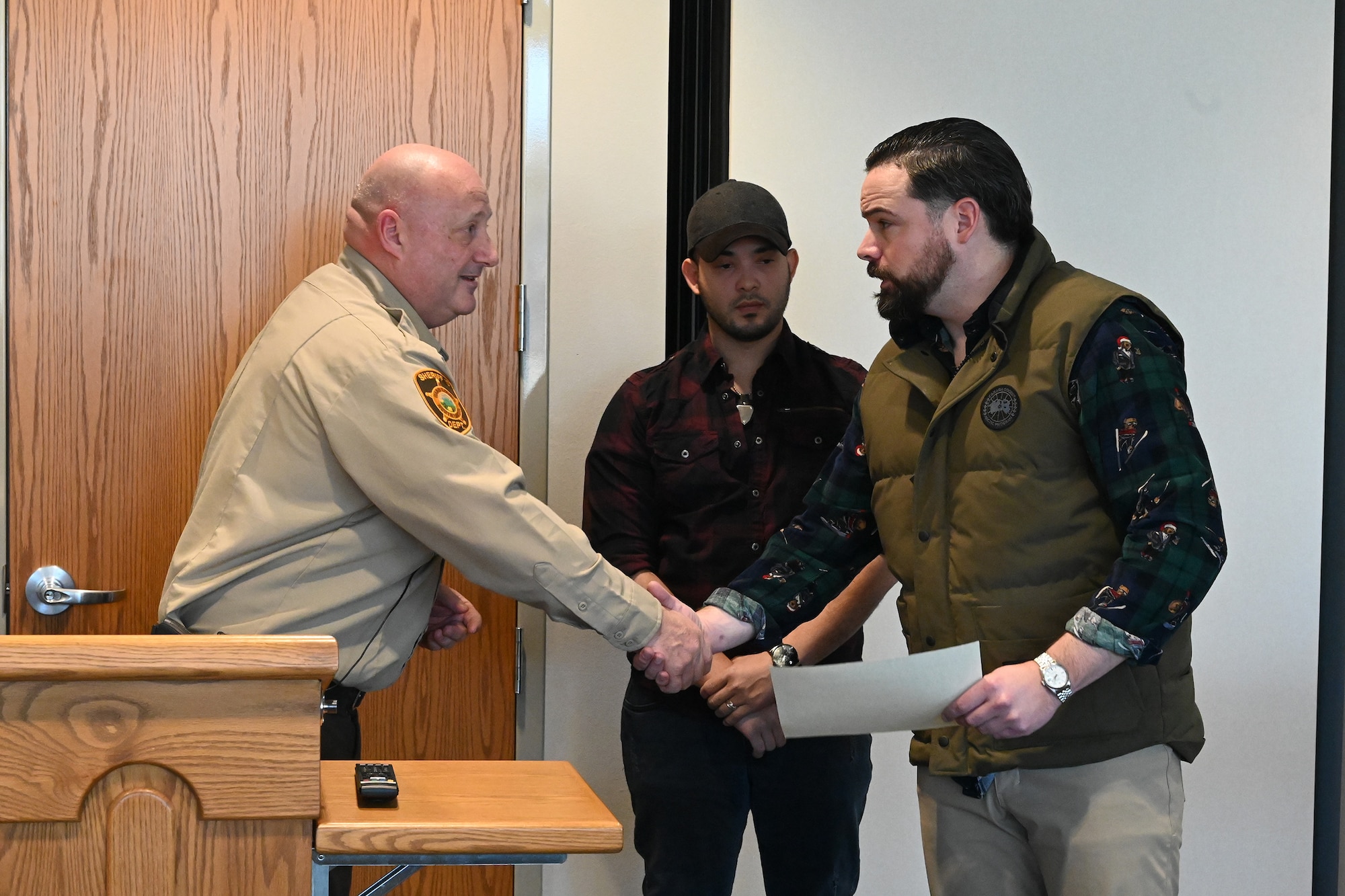 Photo of Ward County Sheriff Bob Roed congratulating Tech. Sgt. Ryan Fontaine and presenting certificate of courage.