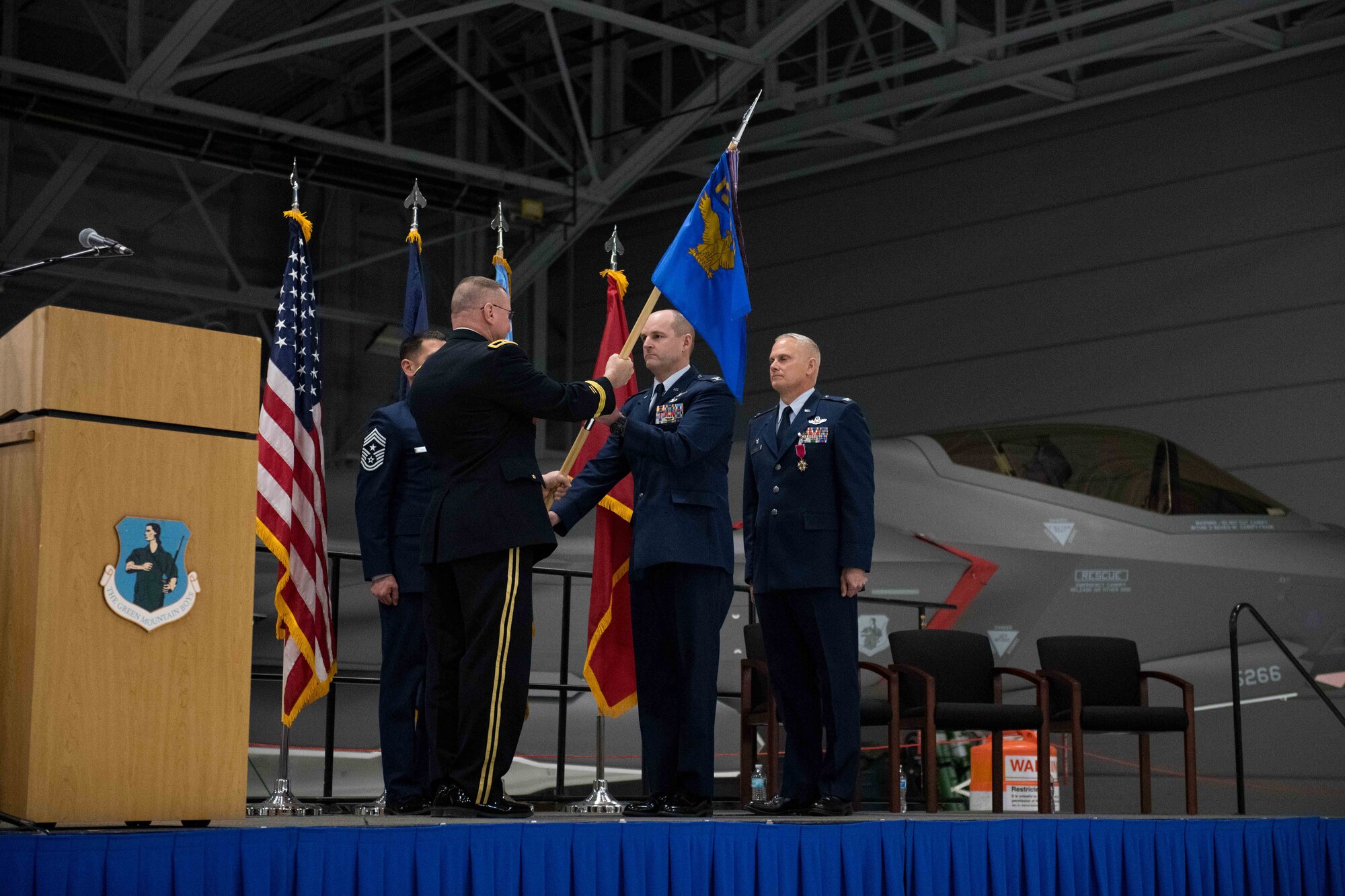 Col. David Shevchik Jr., incoming commander of the 158th Fighter Wing, Vermont Air National Guard, takes the wing guidon from Army Brig. Gen. Greg Knight